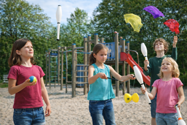 Kinder beim Jonglieren auf dem Spielplatz