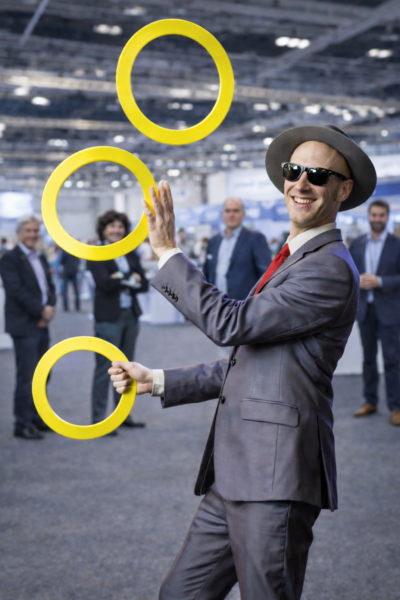 Mann jongliert Rimnge auf Ausstellung